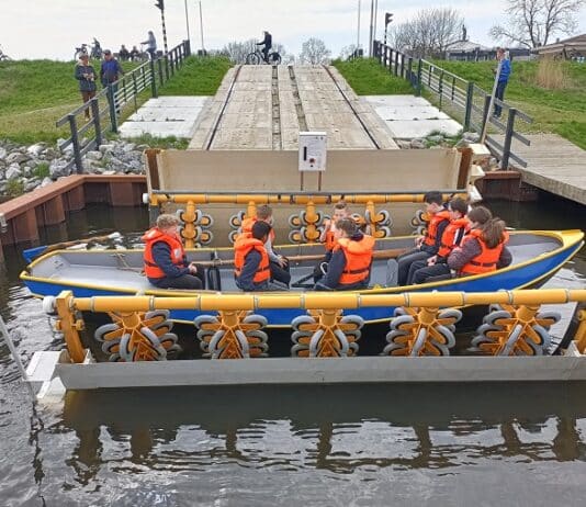 overtoom met zelfbediening - sloep met scoutingleden in de botenwagen die hen over de dijk zet